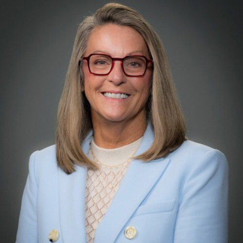 Melanie_Kalmar_500x500 Melanie Kalmar wearing glasses and a light blue blazer, smiling in a professional portrait