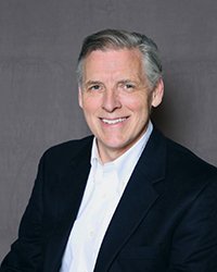 Headshot of Brett Holey with a dark grey backdrop.