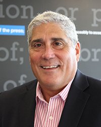 Headshot of Ed Fernandez with a light grey backdrop.
