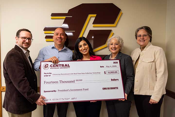 Five adults stand in front of the CMU Action C holding a large check for a Go Grant Initiative