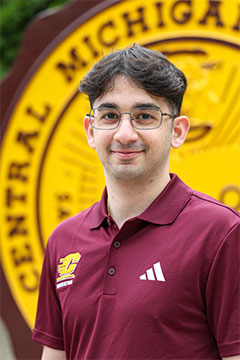 A headshot of SI Leader, Joe Wahbeh, posing outdoors in front of the CMU seal on Warriner Mall. 
